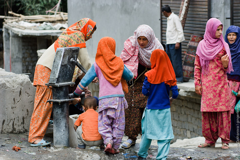 женщины и дети набирают воду из колонки в Каргиле, Индия