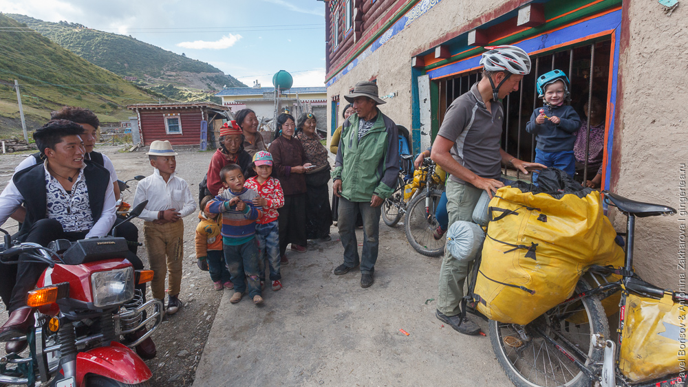 ребенок в велопоходе и тибетцы в традиционной одежде, Сычуань