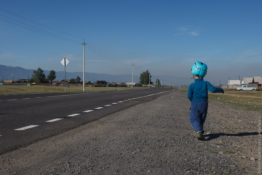 ребенок в велосипедном шлеме идет по дороге в Бурятии